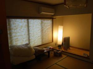 a living room with a window with a table and a lamp at Wholeearth Ryokan Hiroshima in Hiroshima