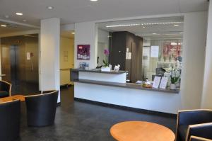 une salle d'attente avec des tables, des chaises et un comptoir dans l'établissement Hotel Cavalli by WP Hotels, à Blankenberge
