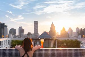 a woman sitting on the rooftop of a building looking at the city at Zenith Sukhumvit Hotel in Bangkok