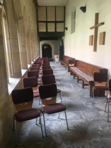 eine Reihe von Stühlen in einer Kirche mit einem Kreuz in der Unterkunft Augustinerkloster Gotha Herberge gGmbH in Gotha