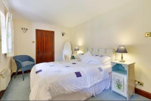 - une chambre avec un grand lit blanc et une chaise dans l'établissement White Lodge House, à Guildford
