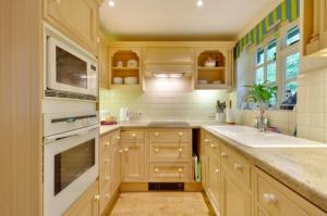 una cocina con electrodomésticos blancos y armarios de madera en White Lodge House, en Guildford