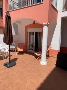 a patio with an umbrella and chairs and a table at Refúgio do Clérigo in Aljezur