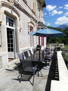 - une table avec des chaises et un parasol sur la terrasse dans l'établissement Chambres d'hôtes " Les Cascatelles", à Ax-les-Thermes