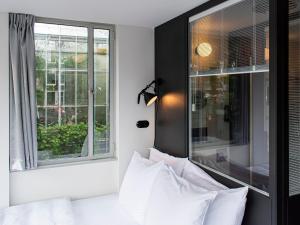 a bedroom with a bed with white pillows and a window at SWEETS - Hortusbrug in Amsterdam