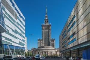 un grand bâtiment avec une tour d'horloge dans une ville dans l'établissement P&O Apartments Śliska, à Varsovie