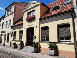 un bâtiment avec des plantes en pot dans une rue dans l'établissement Preliudija, à Klaipėda