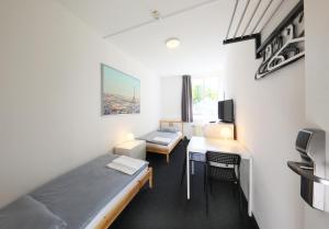 Habitación pequeña con cama y escritorio con mesa. en FANA Pension, en Haar