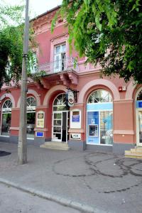 un edificio rosa al lado de una calle en Piros Arany Panzió Kalocsa, en Kalocsa