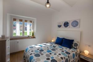 Un dormitorio con una cama con almohadas azules y una ventana en Can Botey, en Ripoll