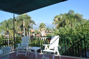 three white chairs sitting on a balcony with palm trees at Blue Coast Sicily in Fondachello