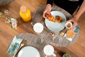 a table with a person holding a plate of croissants at Hôtel Eiffel Saint Charles in Paris