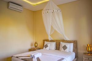 Schlafzimmer mit einem Bett mit weißer Bettwäsche und Vorhängen in der Unterkunft Demank Hidden Guesthouse in Ubud