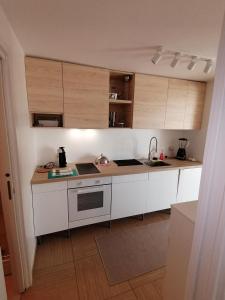 uma cozinha com balcões brancos e armários de madeira em VILLA POP Apartments Crveni Vrh em Crveni Vrh