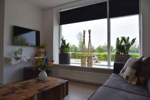 een woonkamer met een bank en een groot raam bij Sfeervol vakantiehuis in Holwerd in Holwerd