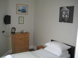 um quarto com uma cama, uma cómoda e uma fotografia em The Kings Arms em Wilmslow
