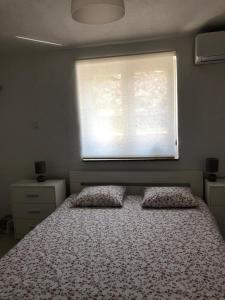 a bedroom with a bed with two pillows and a window at RougeMARIN apartments in Senj