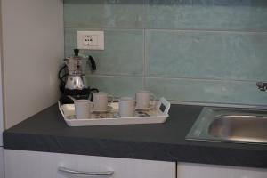 a tray with cups on a counter next to a sink at Albachiara Residence in Chieuti