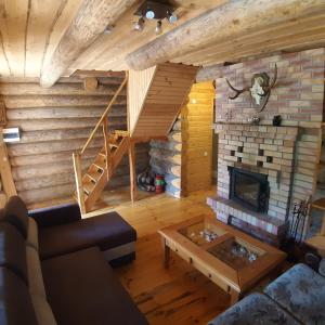 a living room with a fireplace in a log cabin at ŠMITI in (( Čūskumuiža ))