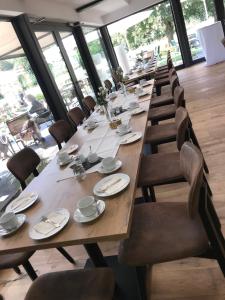 einen langen Holztisch und Stühle in einem Zimmer mit Fenstern in der Unterkunft Landcafe Neumann in Bad Zwischenahn