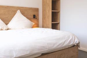 a bedroom with a white bed with a wooden headboard at Ludgerusbrunnen Hotel Mertens in Billerbeck