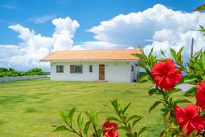 a house with a large yard with red flowers at Sunset Hill Ishigaki in Ishigaki Island