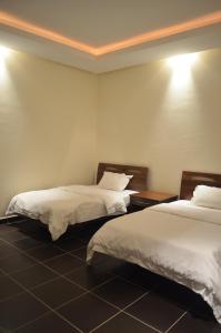 Habitación con 2 camas y sábanas blancas. en Al Juraisi Hotel Apartments, en Riad