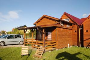 eine Holzhütte mit einem davor geparkt in der Unterkunft Domki u Wladka in Sianożęty