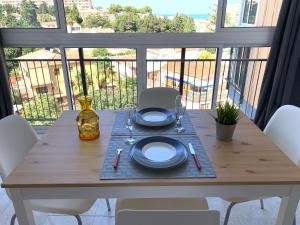 a wooden table with plates and wine glasses on a balcony at Mar del Sur Apartments Benalmádena in Benalmádena