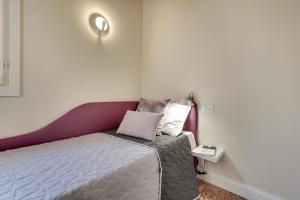 Rugabella Rialto Deluxe في البندقية: غرفة نوم صغيرة مع سرير وطاولة جانبية