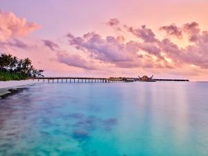 een uitzicht op de oceaan met een pier op de achtergrond bij JOALI Maldives in Raa Atol