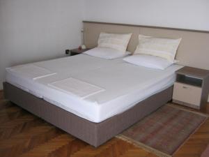 1 cama grande con sábanas y almohadas blancas en Apartments Nestor, en Tribunj