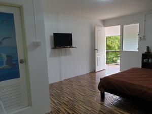 - une chambre avec une télévision murale et un lit dans l'établissement Rung Inn Homestay, à Ranong