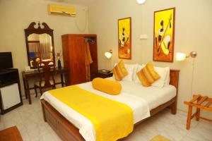 a bedroom with a bed with a yellow blanket on it at Ranveli Beach Resort in Mount Lavinia