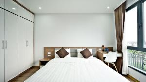 a bedroom with a bed and a desk and a window at ARL Trinh Cong Son Hotel in Hanoi