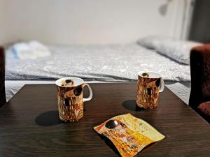 dwa kubki kawy na stole z łóżkiem w obiekcie Krakow Centrum Gurgacza Apartments w Krakowie