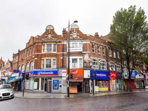 un edificio en una calle de la ciudad con un coche aparcado delante en Broadway Inn en Southall