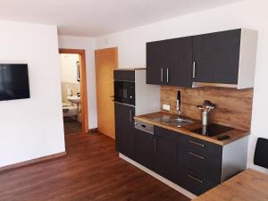 a kitchen with black cabinets and a sink at Garni - Hotel Am Burghuegel in San Candido
