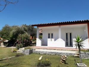 a white house with black doors and a yard at Cala Caterina Rooms in Villasimius