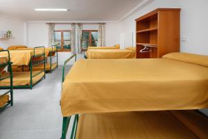 eine Reihe von Betten in einem Zimmer mit gelber Bettwäsche in der Unterkunft Albergue Sierra de Arbe in Naval