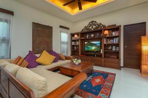 a living room with a couch and a tv at Kokyang Estate by TropicLook in Nai Harn Beach