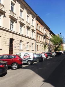 uma fila de carros estacionados em frente a um edifício em Luxury Gold Cracow City Centre 3min Main Sq Old Town em Cracóvia