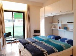 een slaapkamer met twee bedden en een groot raam bij Residentie Noordhinder - Hendrik Consciencelaan 8 - appartement G 0 08 - 8660 De Panne - België in De Panne