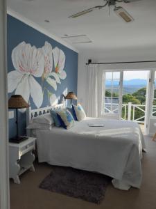 1 dormitorio con 1 cama blanca y un mural de flores en Franmarel, en Plettenberg Bay