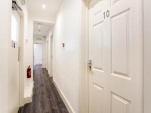 a hallway with a white door and wood floors at The Broadway Hotel - London Heathrow in Southall