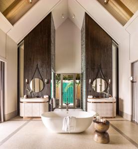 a large bathroom with a tub and two mirrors at JOALI Maldives in Raa Atoll