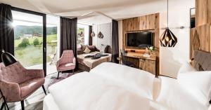 ein Hotelzimmer mit einem Bett und einem großen Fenster in der Unterkunft Alpine Spa Resort Sonnenberg in Meransen