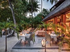 a restaurant with tables and chairs in front of a building at JOALI Maldives in Raa Atoll