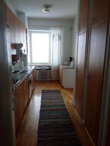 a kitchen with wooden cabinets and a large window at Apartment Widbominkulma in Pori