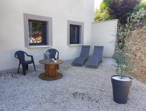 un patio con sillas, una mesa y una pared blanca en Chatimbarbe en Yssingeaux